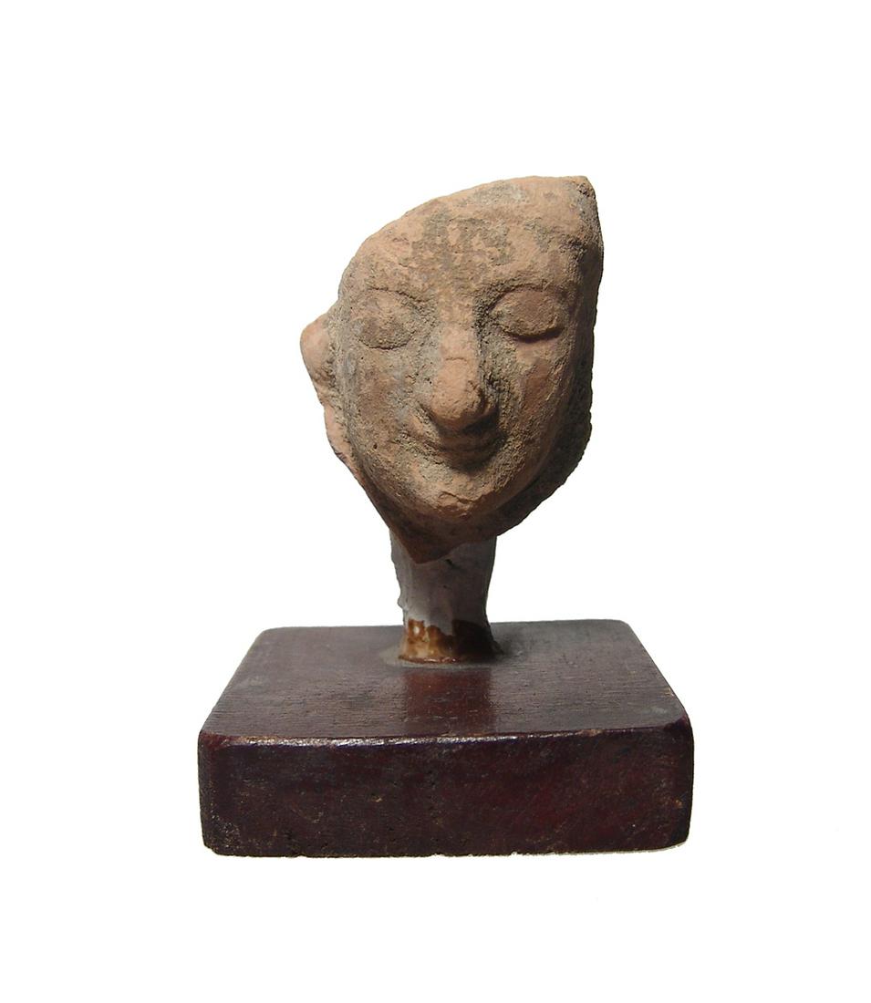 A Greek terracotta head of a man: A Greek terracotta head of a man, c. 6th Century BC, with Archaic features - large almond-shaped eyes and prominent nose. The head with antique wood and plaster mount. H: 3 in(7.6 cm), head by itself: