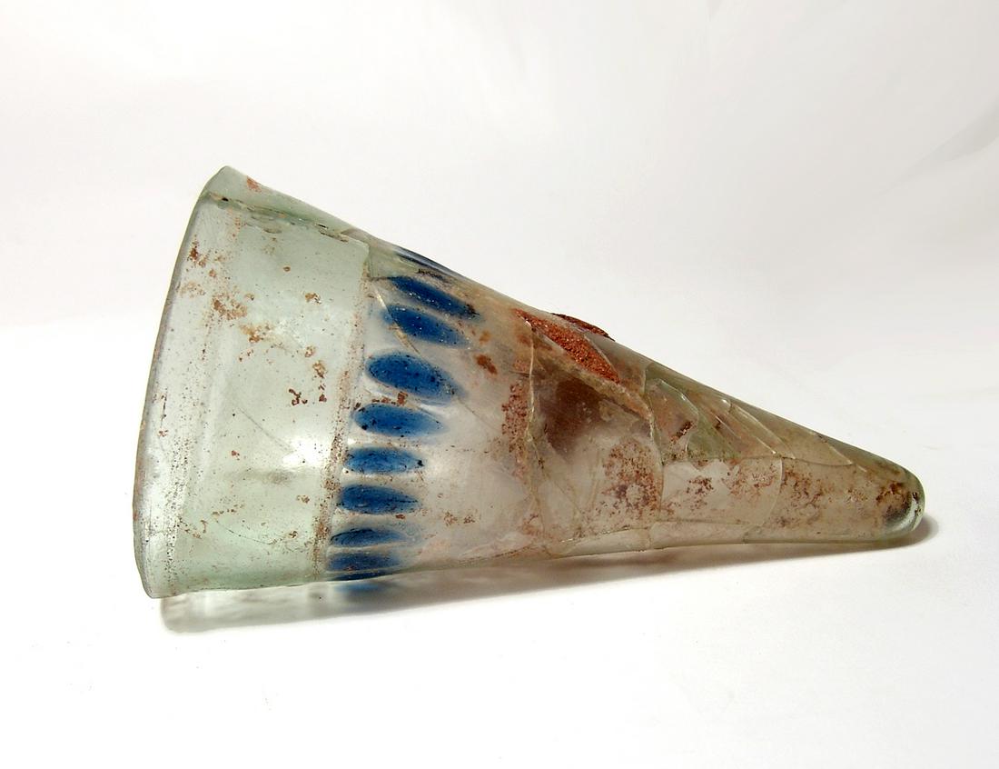 A Roman glass conical beaker, 4th Century AD: A Roman glass conical beaker, 4th Century AD, in pale green glass with two horizontal grooves below the rim above the band over vertical blue decorative blobs of similar sizes, the foot extremely narr