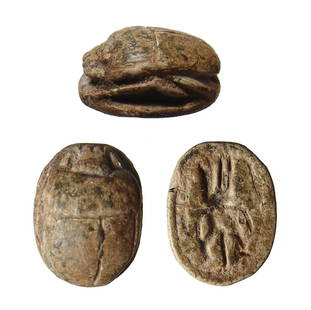 An Egyptian brown steatite scarab, New Kingdom: An Egyptian brown steatite scarab, New Kingdom, c. 1570 - 1075 BC, with nicely carved head, body and legs, on base, facing figure of the god Bes facing wearing feathered headdress, hole lengthwise