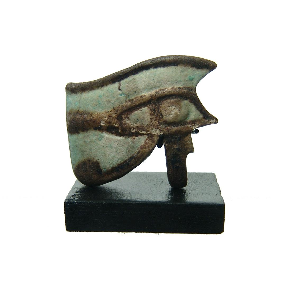 A large Egyptian bicolor faience Eye of Horus amulet: A large Egyptian bicolor faience Eye of Horus amulet, 3rd Intermediate Period, c. 1075 - 664 BC, in pale blue with black details, horizontally pierced for suspension. Amulet measures 32 x 28 mm. Well-