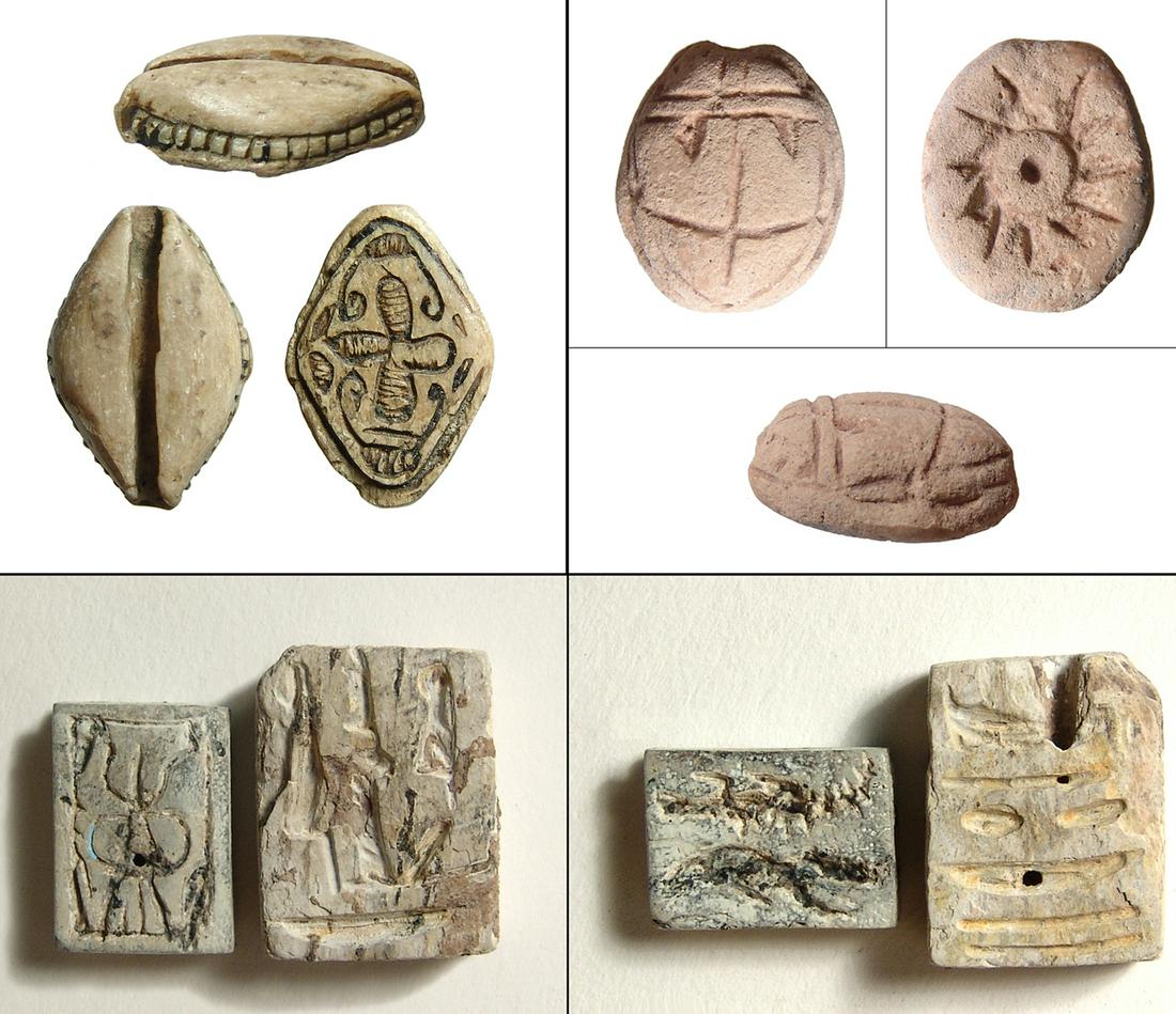 A lot of 4 Egyptian scaraboids and plaques: A lot of 4 Egyptian scaraboids and plaques. Lot includes a steatite cowroid, New Kingdom, c. 1570 - 1075 BC, with lovely cruciform device on base with stylized red browns above and below. 21 x 14.5 mm