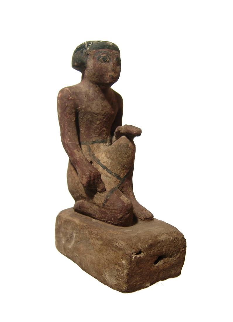 Fantastic Egyptian kneeling wood figure, Middle Kingdom: A fantastic Egyptian kneeling wood figure, Middle Kingdom, c. 2061 - 1690 BC, on a rectangular base, wearing a short Nubian wig and a kilt. The figure is well-preserved with preserved black, red-brown