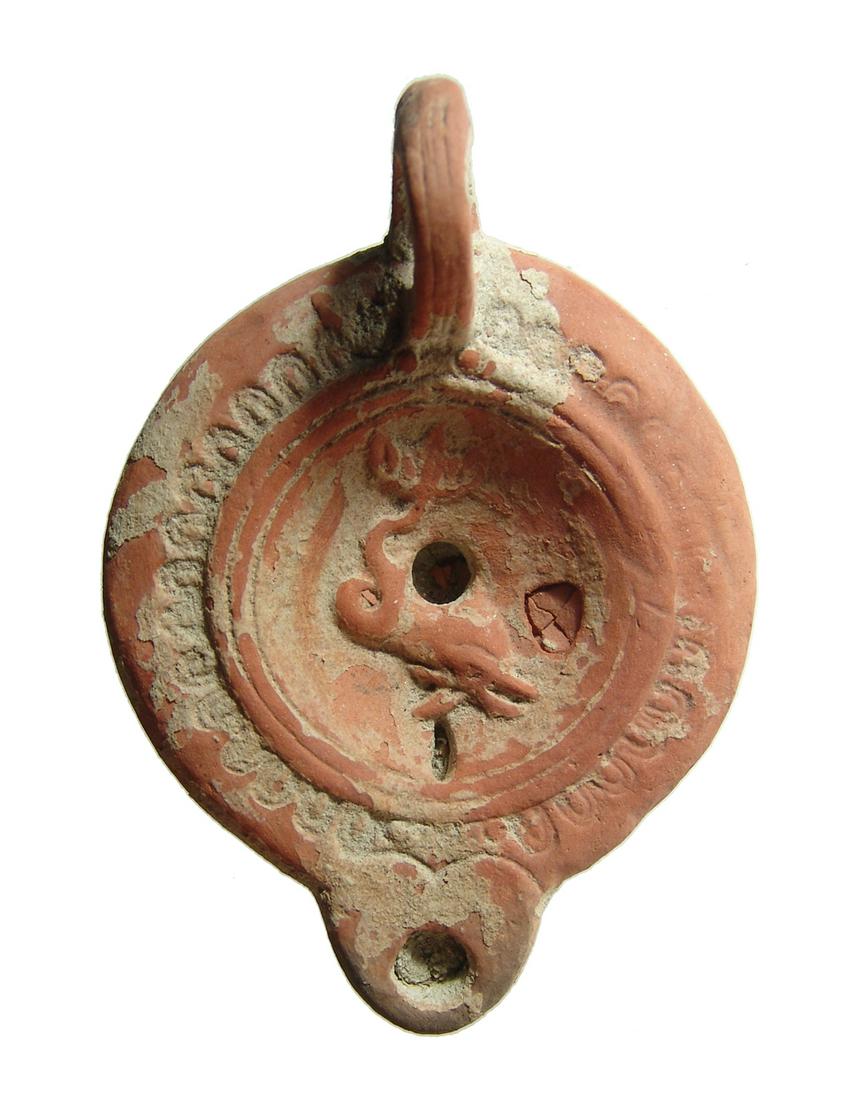 Roman ceramic discus lamp featuring a dolphin: A nice Roman ceramic discus lamp featuring a dolphin, Asia Minor, mid-2nd Century AD, set in a concave discus bordered by grooves and ridges. The shoulder is adorned with ovules with short rounded noz