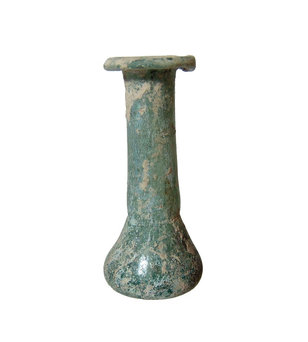 A Roman turquoise blue glass bottle: A Roman turquoise blue glass bottle, c. 1st - 2nd Century AD, the piriform body with indented bottom, the cylindrical neck topped by a widely flared mouth with inward folded rim. H: 2 3/4 in (7 cm). N
