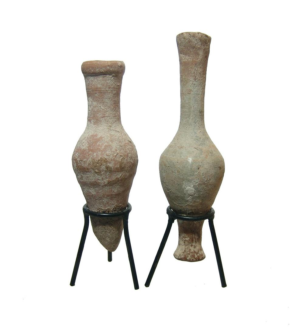A pair of Roman unguent bottles: A pair of Roman unguent bottles, c. 1st - 3rd Century AD, the first is a spindle bottle, H: 5 1/2 in (13.9 cm), and the second is a bottle with body tapering to a point and tall narrow neck flared at 