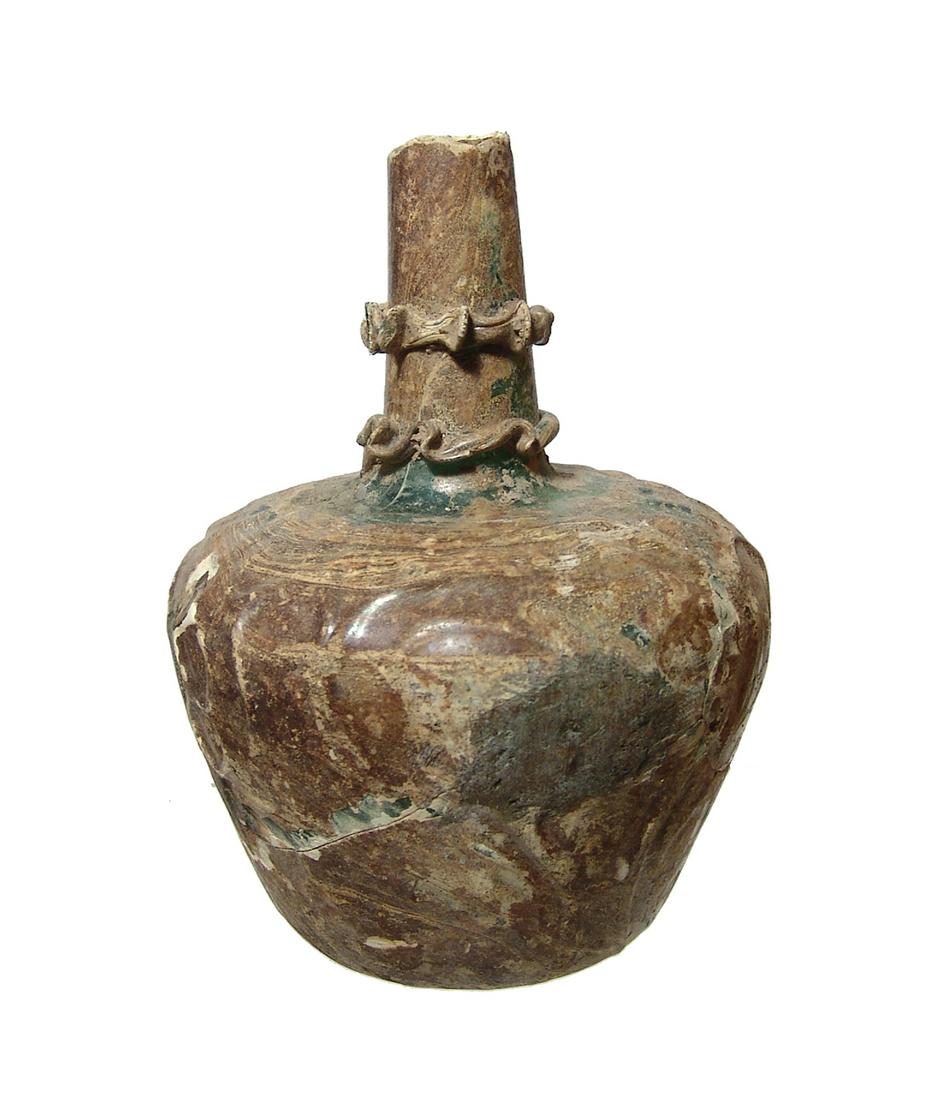 A Near Eastern pattern-molded green glass flask: A Near Eastern pattern-molded green glass flask, c. 10th - 12th Century AD, with an ovoid body bearing a highly stylized design containing swirls and circles. A tubular neck rises from the top of the 