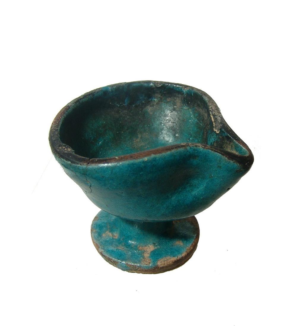 A well-preserved Islamic blue-glazed oil lamp: A well-preserved Islamic blue-glazed oil lamp, c. 12th - 13th Century, on a pedestal foot, the glaze exceptionally preserved with carbon deposits around the spout. 2 3/8 x 3 in (6 x 7.6 cm). Ex collec