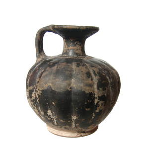 A Greek black glazed squat lekythos: A Greek black glazed squat lekythos, c. 4th Century BC, with vertical ribbing giving it a gourd-like appearance and narrow flared foot. The neck is short with widely flared mouth and strap handle. An