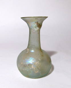 An attractive Roman pale green glass bottle: An attractive Roman pale green glass bottle, c. 2nd - 3rd Century AD, the body piriform with indented bottom, tubular beck and widely flared mouth with rounded rim. H: 4 1/4 in (10.8 cm).