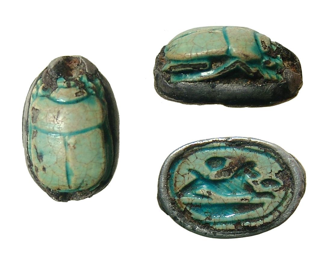 An Egyptian faience scarab set in silver bezel: An Egyptian faience scarab set in silver bezel, New Kingdom, c. 1570 - 1075 BC, with remnants of green glaze and depicting a springing hare on the base. The remains of a silver bezel can be found arou