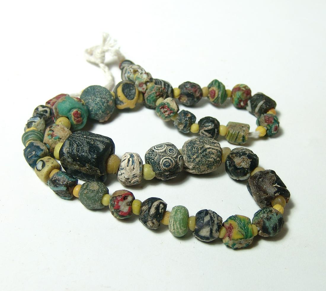 A lovely strand of vibrant ancient glass beads: A lovely strand of vibrant ancient glass beads, Roman through Islamic, including several lovely eye beads. The beads are nicely preserved with vibrant color and strung with small yellow glass beads as