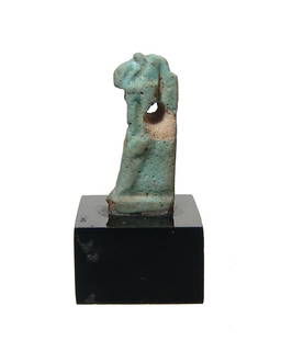 An Egyptian faience amulet of Thoth, Ptolemaic: An Egyptian faience amulet of Thoth, Ptolemaic, c. 332 - 30 BC, with horizontal suspension hole through the vertical plinth down back. H: 27 mm. Mounted on a black lucite base. Ex collection of