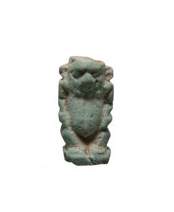 An Egyptian pale blue faience amulet of Bes: An Egyptian pale blue faience amulet of Bes, c. 664 - 30 BC, standing nude on integral base, with leonine features and a vertical plinth at back. L: 22 mm. Light deposits. Ex New Orleans private