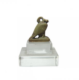 An Egyptian faience amulet in the form of a falcon: An Egyptian faience amulet in the form of a falcon, Late Period, c. 664 - 332 BC, representing Horus, with light green glaze and suspension loop at neck. 2.5 x 2.1 cm. Mounted on lucite base. Ex