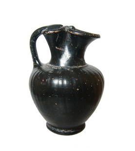 An Etruscan Malacena-ware trefoil olpe: An Etruscan Malacena-ware trefoil olpe, c. 300 - 250 BC, the body with light vertical ribbing and ring foot, the trefoil spout well-modeled with loop handle. Well-preserved with glossy black