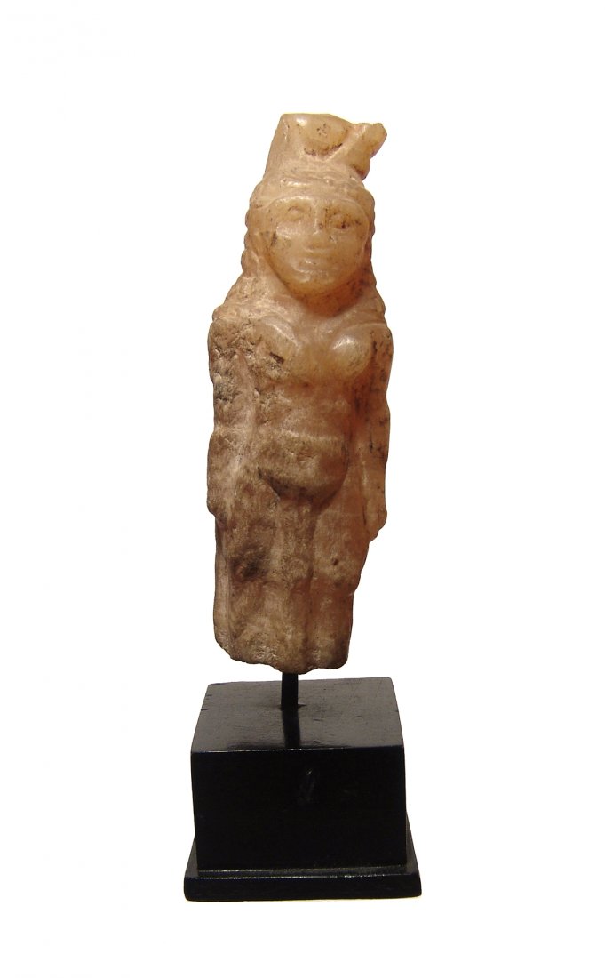 An Egyptian alabaster figure of the goddess Hathor: An Egyptian alabaster figure of the goddess Hathor, Late Period, c. 664 - 30 BC, wearing a tight-fitting gown and a headdress composed of cow's horns and a solar disk. Her features are rounded and qui