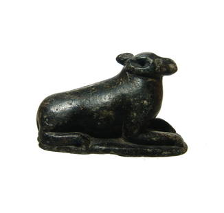 Egyptian serpentine figure of a recumbent dog: A wonderful Egyptian serpentine figure of a recumbent dog, c. 1075 - 332 BC, on integral rectangular base, the head held high with detailed eyes, nose and snout and tapered ears. 1 1/4 x 2 1/4 in