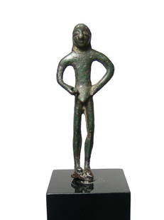 An Archaic Greek bronze male figure: An Archaic Greek bronze male figure, c. 6th Century BC, the head with large eyes and arms at side, right hand once held an implement. Rich olive-green patina. H: 3 1/2 in (8.9 cm). Well-preserved, top