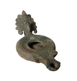 A nice Roman bronze lamp with head of a griffin: A nice Roman bronze lamp with head of a griffin, 1st Century AD, which emerges from a palmette handle guard, loop below. The body round and shallow with incised concentric rings around the fill-hole,