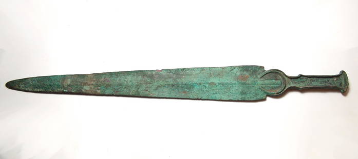 A large Near Eastern bronze short sword: A large Near Eastern bronze short sword, c. 1200 - 800 BC, cast as one piece, the flanged hilt with wedge-shaped pommel, lappets now lost, the flanges also encompassing a crescent extending onto the