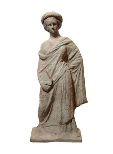 Hellenistic terracotta figure of a standing woman: A lovely Hellenistic terracotta figure of a standing woman, c. 3rd - 2nd Century BC, on integral rectangular base, wearing chiton and himation, a large wreath on her head. She stands with left arm beh