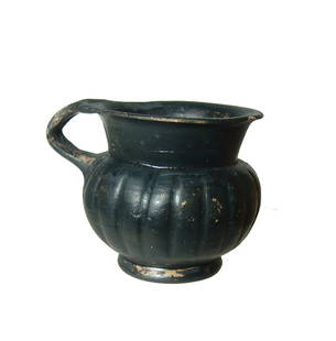 A Greek black-glazed olpe, Magna Graecia: A Greek black-glazed olpe, Magna Graecia, 4th Century BC, the ribbed sides in imitation of metal-ware and split handle. H: 2 2/3 in (6.9cm). Light deposits. Ex UK private collection acquired from