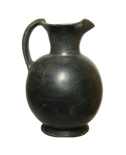 A lovely Etruscan bucchero trefoil olpe: A lovely Etruscan bucchero trefoil olpe, c. 600 - 550 BC, the ovoid body with flared foot and trefoil pouring spout with single handle. The vessel is well-preserved with glossy surfaces and light