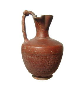 A Roman terra sigillata pitcher: A Roman terra sigillata pitcher, c. 3rd Century AD, with trefoil pouring spout, the handle decorated with a knot of Hercules and the body decorated with a repeated, raised floral pattern. H: 6 1/4 in