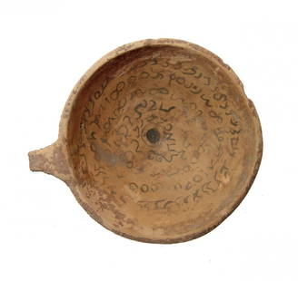 A nice Mesopotamian incantation cup: A nice Mesopotamian incantation cup, c. 7th Century AD, the shallow bowl with spiraling band of Syriac text in dark brown slip around a central 'eye', a small looped handle at edge. L: 5 1/2 in (13.8