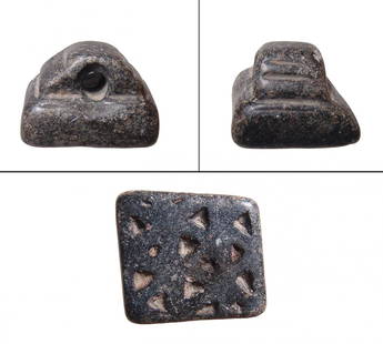 A Mesopotamian black steatite stamp seal: A Mesopotamian black steatite stamp seal, 4th Millennium BC, the base rectangular and incised with rows of triangles, the top with large handle decorated with grooves. 25 x 27 mm. Wear from use. Cf.