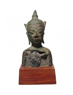 A Thai bronze bust of Buddha: A Thai bronze bust of Buddha, c. 16th - 17th Century, wearing a crown, his features well-detailed. H: 2 3/4 in (7 cm). Nice patina and mounted on antique wood base. Ex collection of Lucy Maxym, CA.