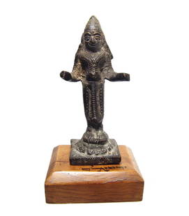 A Southeast Asian bronze figure of a deity: A Southeast Asian bronze figure of a deity, 18th - 19th Century, elaborately attired and standing on a decorated base. H: 3 7/8 in (9.8 cm). Nicely patinated and with a beautiful antique wood base