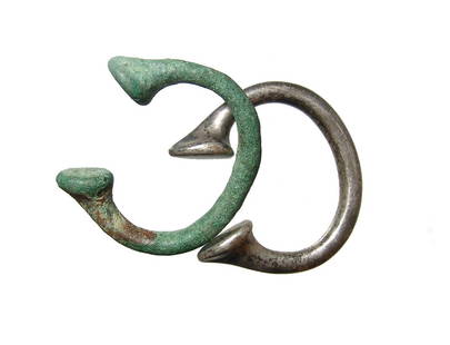 A pair of African manillas, 18th Century: A pair of African manillas, 18th Century, a form of currency in West Africa, one of bronze and the other of silver and both from the Late British period. Largest 2 3/8 x 2 1/8 in (6 x 5.4 cm). Ex