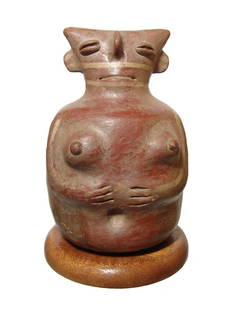 A large Vicus effigy vessel in the form of a woman: A large Vicus effigy vessel in the form of a woman, c. AD 100 - 700, with stylized features and hands below her breasts. The spout at back is joined to the main body of the vessel by a looped strap