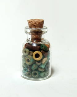 A small bottle filled with Egyptian faience beads: A small bottle filled with Egyptian faience beads, Late Period, c. 664 - 332 BC, multi-colored disc and tubular beads of high quality. Bottle measures about 1 in (2.5 cm) in height with cork. Beads: