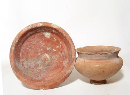 A pair of Late Bronze Age bowls: A pair of Late Bronze Age bowls, c. 1550 - 1200 BC, the first of lower profile in a deep orange ware, 2 1/8 x 7 ¾ in (5.4 x 19.7 cm), the second a creme buff bowl with narrow pedestal base and