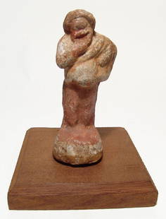 A wonderful Hellenistic terracotta figure of an actor: A wonderful Hellenistic terracotta figure of an actor, c. 3rd - 2nd Century BC, wearing a tunic and pants, cradling an uncertain object in his left arm and his right hand at his chin The figure is