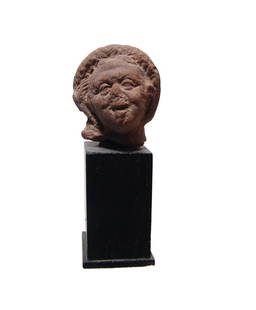 Romano-Egyptian terracotta head of aged Harpokrates: A Romano-Egyptian terracotta head of aged Harpokrates, 2nd - 3rd Century AD, wearing rolled diadem and side-lock, his features rather grotesque per the style. Deposits throughout. H: 1 4/5 in