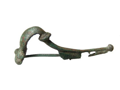 A large Roman Kraftig profilierte bronze fibula: A large Roman Kraftig profilierte bronze fibula, 1st Century AD, the body arched with original coil and catch, which is adorned with two rectangular cut-outs. L: 3 1/8 in (8 cm). Ex Boston private