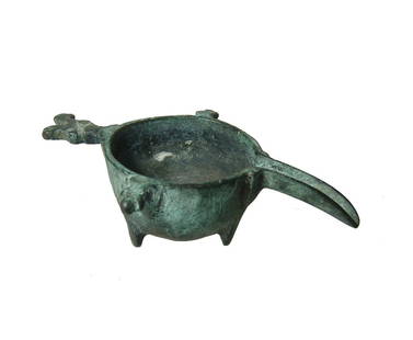 A Byzantine bronze oil lamp filler: A Byzantine bronze oil lamp filler, c. 5th - 6th Century AD, with deep rounded bowl, long channeled spout curved downward, projection to either side and a zoomorphic handle at back in the form of a
