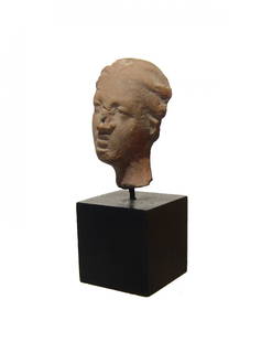 A nice Greek terracotta female head: A nice Greek terracotta female head, c. 3rd - 2nd Century BC, her head slightly tilted to her left, features quite attractive with hair styled back in waves. H: 1 1/2 in (3.7cm). Mounted on black wood