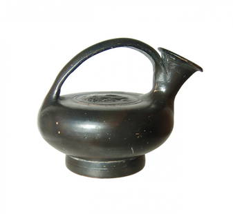 A cute Greek guttus with head of a gorgon: A cute Greek guttus with head of a gorgon, Magnia Graecia, 4th Century BC, with smooth rounded shoulder and center handle attaching the shoulder to edge of spout. The facing head of the gorgon with
