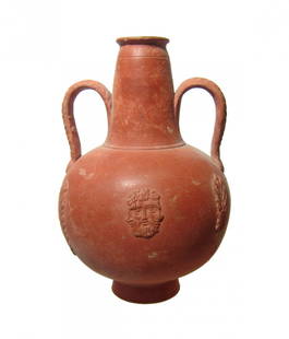 A lovely Roman two-handled orange-ware juglet: A lovely Roman two-handled orange-ware juglet, North Africa, c. 4th - 5th Century AD, the round body with raised narrow base and decorated with a central tricephalic bearded head in relief, palm