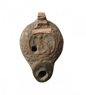 Miniature Roman oil lamp with cherubic figure and: A miniature Roman oil lamp with cherubic figure and female in central discus, 1st Century AD, with floral decoration around the shoulder and maker's mark on bottom. L: 2 in (5.1cm). Light deposits