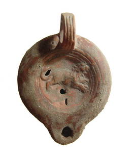 A Roman ceramic discus lamp depicting a lion: A Roman ceramic discus lamp depicting a lion, 2nd Century AD, the deeply concave discus bordered by grooves and ridges, the shoulder plain with rounded nozzle handle and ring handle with vertical groo