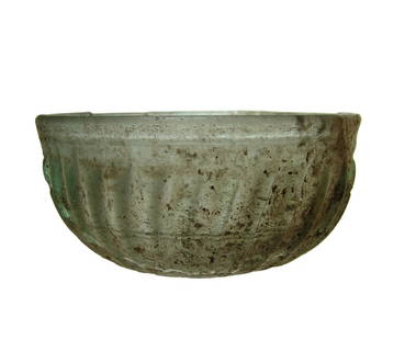 An attractive deep ribbed Roman glass bowl: An attractive deep ribbed Roman glass bowl, 1st Century AD, mold-formed in light green-blue glass with prominent vertical ribbing, flat base and three wheel cut grooves in the interior. Dia: 4 7/8 in
