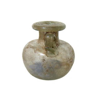 Roman glass aryballos with remnants of original: A Roman glass aryballos with remnants of original contents, c. 1st - 2nd Century AD, in pale yellow-green glass, the rounded body with indented bottom, a short cylindrical neck topped by a wide, flat