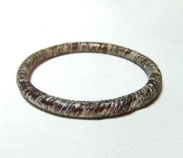 A Roman orange glass ribbed bracelet: A Roman orange glass ribbed bracelet, c. 1st - 3rd Century BC, nicely made with a twisted appearance and lovely iridescence. Dia: 3 1/2 in (8.9 cm). Ex Pennsylvania private collection.