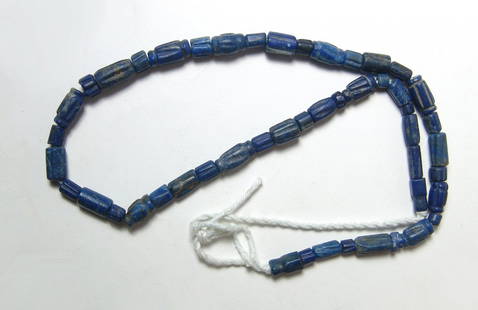A strand of lapis lazuli beads, Central Asia: A strand of lapis lazuli beads, Central Asia, c. 14th - 15th Century, all are barrel-shaped of varying lengths, many with vertical ribbing and collars at either end. Strand measures 18 in (45.6 cm).