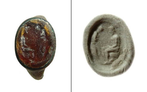 A Roman bronze ring with orange glass intaglio: A Roman bronze ring with orange glass intaglio, c. 1st - 2nd Century AD, perhaps once gilded, the stone depicts a nude female standing before a seated nude man. Intaglio: 13 x 11 mm; Ring: 21 x 18